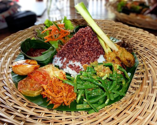A traditional Indonesian meal featuring tempeh, rice, and fresh vegetables