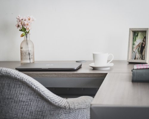 Office worker stretching arms while sitting at a desk with laptop